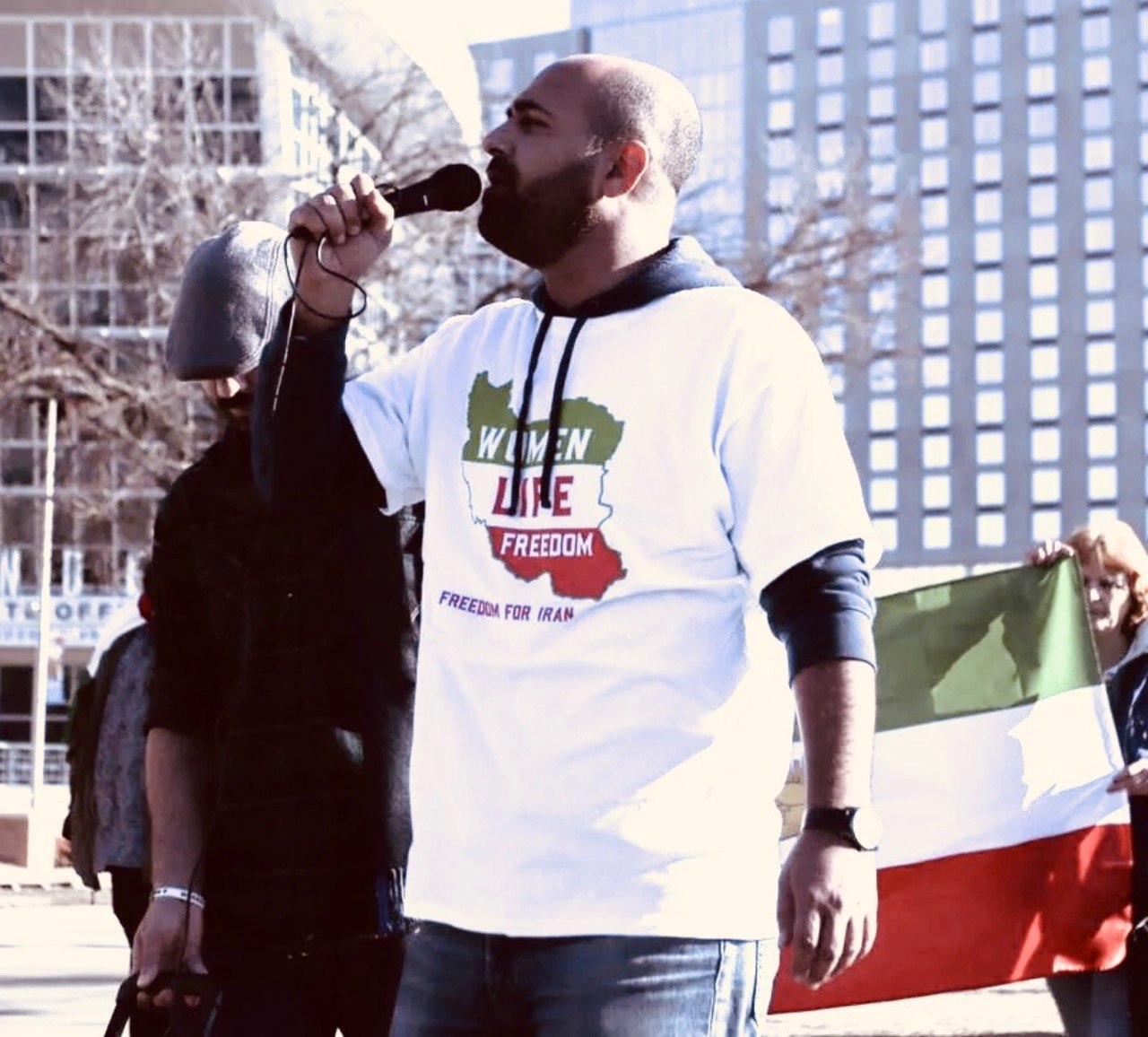Peyman speaking at a Women Life Freedom rally wearing a Freedom for Iran shirt
