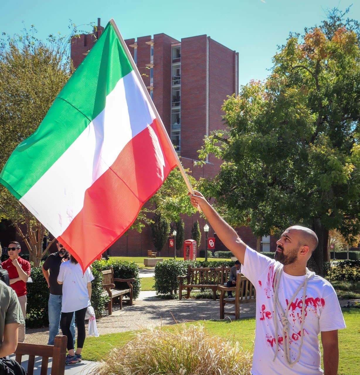 Peyman raising the Iranian flag at an OU campus rally